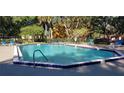 Community pool surrounded by lounge chairs, trees, and fencing for a relaxing recreational area at 5287 Images Cir # 303, Kissimmee, FL 34746