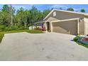 Wide driveway leading to a tan home with a 2-car garage, surrounded by green lawn and trees in the background at 536 Bristol Cir, Kissimmee, FL 34758
