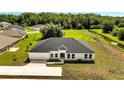 New construction home features a spacious lot with lush green grass and mature trees at 547 Viceroy Ct, Kissimmee, FL 34758