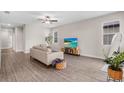 Bright living room featuring wood-look floors, a ceiling fan, and neutral decor, creating a modern and inviting space at 7848 Somersworth Dr, Kissimmee, FL 34747