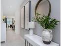 Bright hallway with modern decor, leading to the dining room with a decorative mirror and plant at 8937 Amelia Downs Trl, Kissimmee, FL 34747