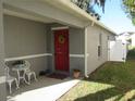 Inviting front entry with red door, white chairs, and landscaping at 2608 Whitewood Road, Mulberry, FL 33860