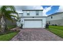 Two-story home featuring a brick driveway, white garage door, and neatly landscaped yard at 1564 Eucalyptus Way, Davenport, FL 33837