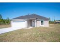 New single-Gathering home with a gray roof, white garage, and long concrete driveway at 2700 Laguna Dr, Indian Lake Estates, FL 33855