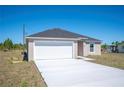 New single-Gathering home with a gray roof, white garage, and long concrete driveway at 2700 Laguna Dr, Indian Lake Estates, FL 33855