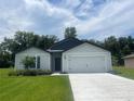 Alluring single-story home featuring a lush green lawn, a practical two-car garage, and pleasing curb appeal at 4270 Sw 143Rd Lane Rd, Ocala, FL 34473