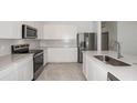 Beautiful kitchen featuring stainless steel appliances, white cabinets and large island with sink at 6826 Sw 90Th Loop, Ocala, FL 34476