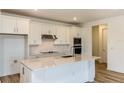 Modern kitchen featuring white cabinets, stainless steel appliances, and a center island with quartz countertops at 4457 Sw 84Th Street Rd, Ocala, FL 34476