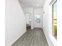 Bright entryway with grey wood-look flooring, half bathroom, and stairway at 3740 Bergamot St, Lake Alfred, FL 33850