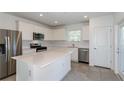 Modern kitchen with stainless steel appliances, white cabinets, a large island, and a tile backsplash, perfect for cooking at 9080 Wildlight Trl, Wildwood, FL 34785