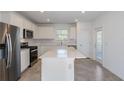 Modern kitchen with stainless steel appliances, white cabinets, a large island, and a tile backsplash, perfect for cooking at 9080 Wildlight Trl, Wildwood, FL 34785