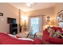 Bright living room with a ceiling fan, comfortable red sofa, and sliding glass doors to the outdoor balcony at 308 New Providence # 308, Davenport, FL 33897