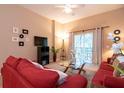 Comfortable living room featuring a plush red sofa, TV, and sliding glass doors to the outdoor balcony at 308 New Providence # 308, Davenport, FL 33897