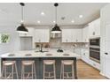 Bright kitchen features a large island with bar seating, stainless appliances, and modern pendant lighting at 6086 Sacred Oak Ave, Mount Dora, FL 32757