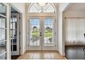 Bright foyer featuring double glass doors, tile flooring, and elegant transom window at 5407 County Road 125, Wildwood, FL 34785