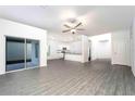 Bright open-plan living room with modern ceiling fan, gray flooring, and sliding glass doors at 13490 Leaping Water Way, Astatula, FL 34705