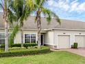 Beautiful townhome featuring lush landscaping, mature palm trees, and a well-maintained lawn at 3825 Quaint Ln # C, Clermont, FL 34711