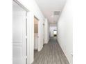 Bright hallway with grey wood-look floors and white doors at 13454 Leaping Water Way, Astatula, FL 34705