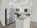 Bright kitchen features stainless steel appliances, white cabinets, gray countertops and central island at 13489 Leaping Water Way, Astatula, FL 34705