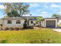 Charming one-story home with mature landscaping, gray garage door, and green lawn at 3203 S Polk Ave, Lakeland, FL 33803