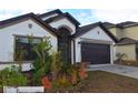 Single-story home featuring a two-car garage, an arched entryway, and well-kept landscaping at 1051 Woodlark Dr, Haines City, FL 33844