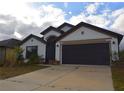 Attractive single-story home featuring a two-car garage, a well-kept lawn, and a welcoming entryway at 1051 Woodlark Dr, Haines City, FL 33844