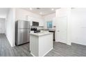 Bright kitchen featuring a center island, stainless steel appliances and grey wood floors at 13469 Leaping Water Way, Astatula, FL 34705