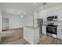 Modern kitchen with stainless appliances, granite countertops, island, and wood floors open to living area at 13469 Leaping Water Way, Astatula, FL 34705