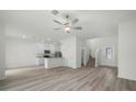 Bright, open-concept living space with wood-look flooring, a ceiling fan, and a view of the modern kitchen at 13446 Leaping Water Way, Astatula, FL 34705