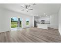 Bright open-plan living room with wood-look floors and a modern kitchen featuring stainless steel appliances at 13485 Leaping Water Way, Astatula, FL 34705