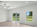 Bright living room featuring wood-look floors, large windows and access to a covered patio at 13485 Leaping Water Way, Astatula, FL 34705