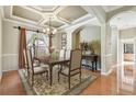 Elegant dining room with a chandelier, coffered ceilings, and a large window overlooking a tropical view at 2024 Capri Ln, Mount Dora, FL 32757