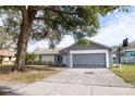Single story house with a gray garage door and mature landscaping at 7631 Lewis Rd, Lakeland, FL 33810