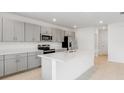 Bright kitchen with stainless steel appliances, gray cabinetry, and a spacious center island with a sink at 4430 Petunia St, Lake Hamilton, FL 33851