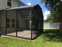 This outdoor patio is screened in with black frames and overlooks a luscious yard at 745 Marsh Reed Dr, Winter Garden, FL 34787