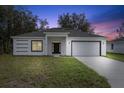White house with gray roof, black door, and two-car garage at dusk at 1305 Congo Ct, Poinciana, FL 34759