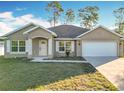 Tan house with white garage door, shutters, and landscaping at 16962 Sw 40Th Cir, Ocala, FL 34473