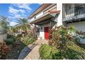 Inviting front entrance with red door, lush landscaping and stone path at 6141 Palmetto Dr, Indian Lake Estates, FL 33855