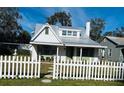 Quaint cottage exterior featuring a metal roof and white picket fence at 415 Avenue K Ne, Winter Haven, FL 33881