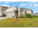 Tan house with a two-car garage and a small tree at 1536 Axel Cir, Winter Haven, FL 33880
