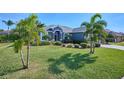 Single-story home with a landscaped lawn, palm trees, and a two-car garage at 4545 Mandolin Blvd, Winter Haven, FL 33884