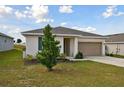 One-story house with a two-car garage and a tree in the front yard at 1734 Hill Top Dr, Dundee, FL 33838