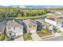 Aerial view of a two-story home with landscaping and a two-car garage near a pond and wooded area at 163 Tiny Flower Rd, Davenport, FL 33837