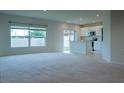 A bright and open-concept living room featuring plush carpeting and a view of the modern kitchen at 2871 Parkfield Rd, St Cloud, FL 34772