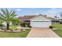 One-story house with a brick driveway and palm tree at 3096 Lansing Way, The Villages, FL 32162