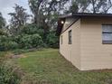 Side view of a tan house with brown trim and green lawn at 112 Jasper St, Bushnell, FL 33513