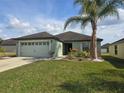 Inviting single-story home with attached garage and lush green lawn with a palm tree at 2157 Geneva Dr, Lakeland, FL 33805