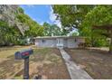 Quaint one-story home with a grey exterior, a well-manicured lawn, and charming front yard foliage at 1412 E Main St, Lakeland, FL 33801