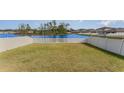 Spacious backyard with a well-maintained lawn and white picket fence, offering serene pond views at 2133 Old Mining Rd, Lakeland, FL 33801