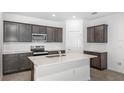 Modern kitchen with stainless steel appliances, a central island, stylish gray cabinets, and white backsplash at 8223 Sw 52Nd Lane Rd, Ocala, FL 34481